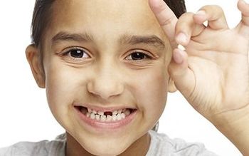 Smiling child making an OK sign with fingers near their face, against a white background