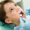 Child receiving a dental exam while a dentist uses tools inside their mouth