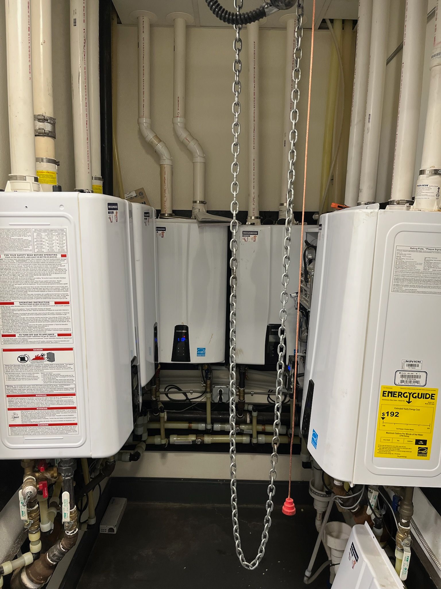 Two water heaters are hanging from chains in a room.