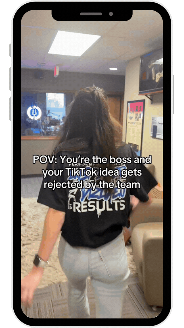 A person walking away into an office, wearing a black t-shirt with the text 