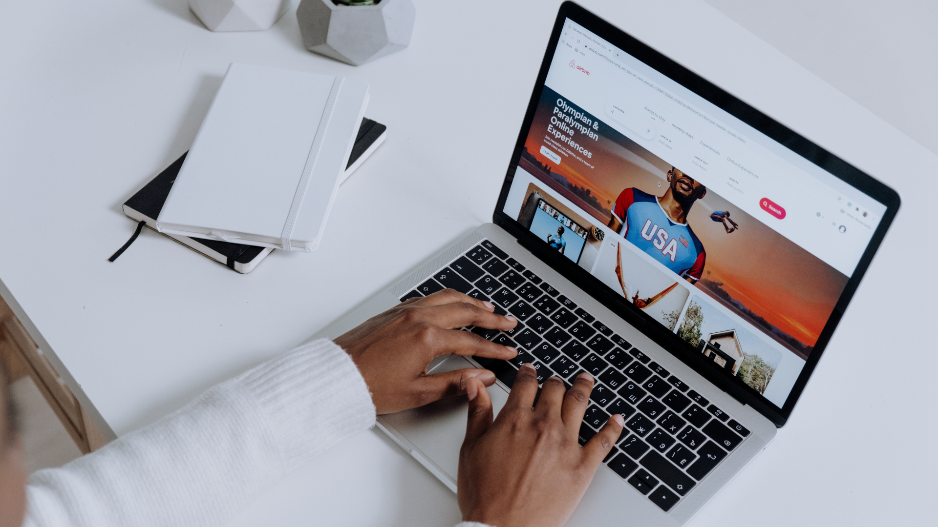 Hands typing on a laptop displaying a website on a white desk