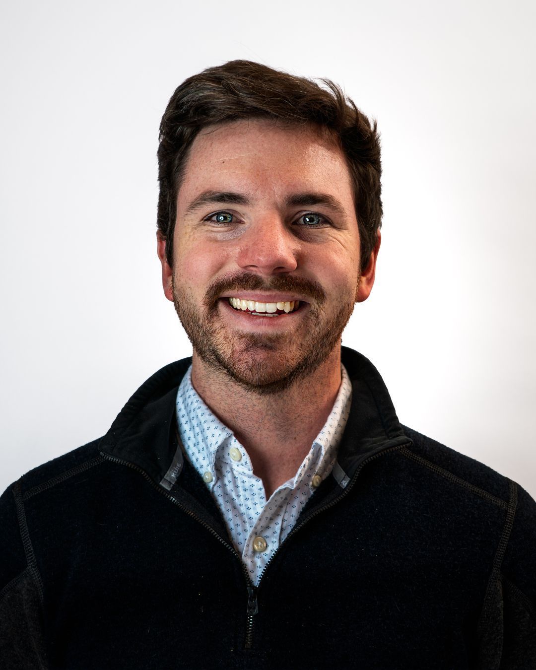 A man in a suit and tie is smiling for the camera