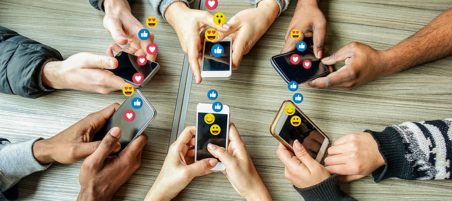 Hands holding smartphones in a circle on a table, with colorful app icons floating above each screen.