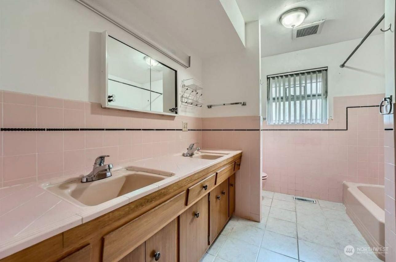 A bathroom with two sinks, a mirror and a tub