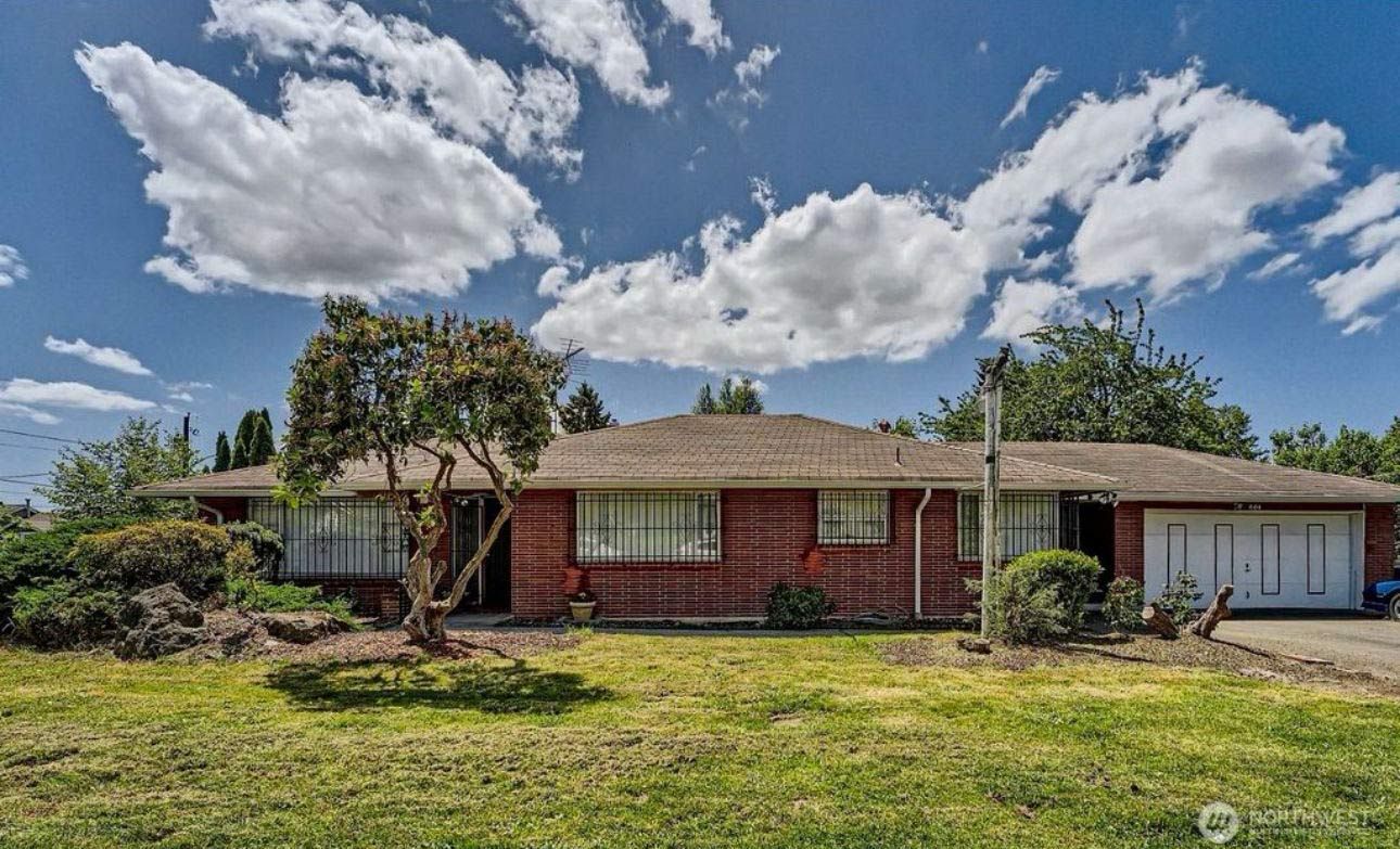 A brick house with a garage and a tree in front of it