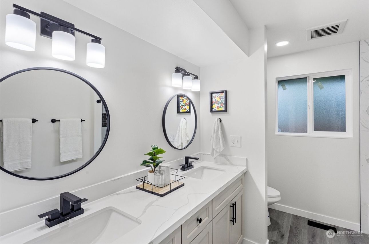 A bathroom with two sinks two mirrors and a toilet