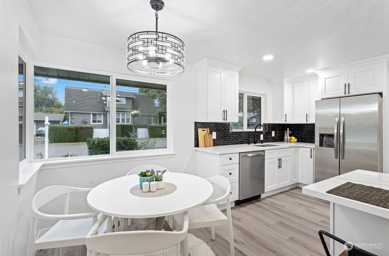 A kitchen with white cabinets, stainless steel appliances, a round table and chairs