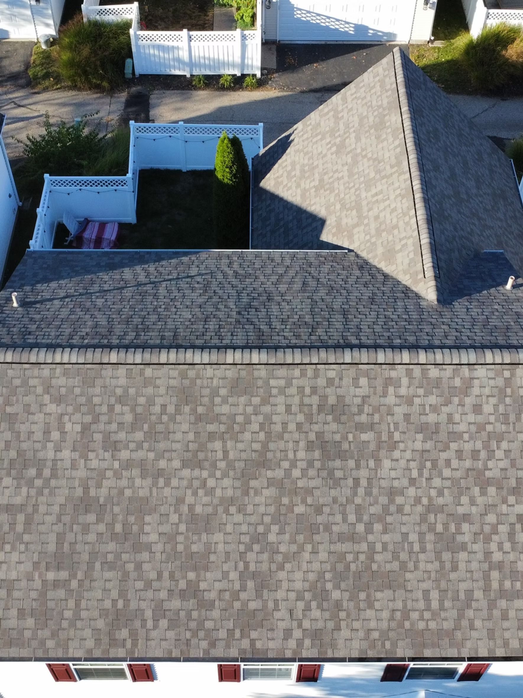 Overhead view of rooftops, fences, and a small yard with a tree.