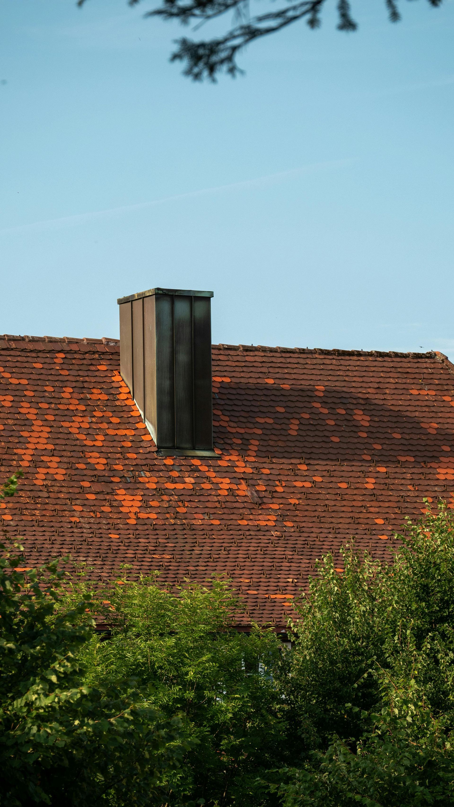 Red tile roof of a house with a wooden chimney