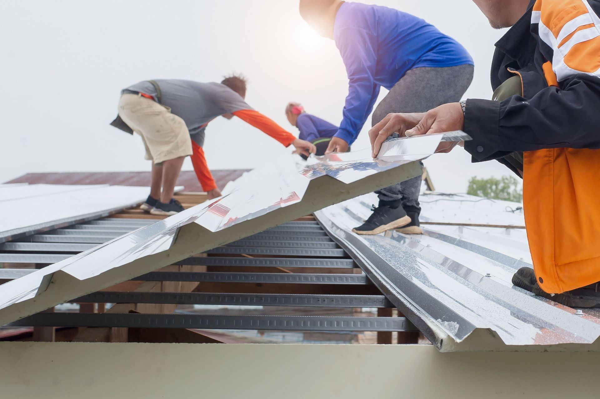 Roofers installing corrugated metal roofing sheets on a house.
