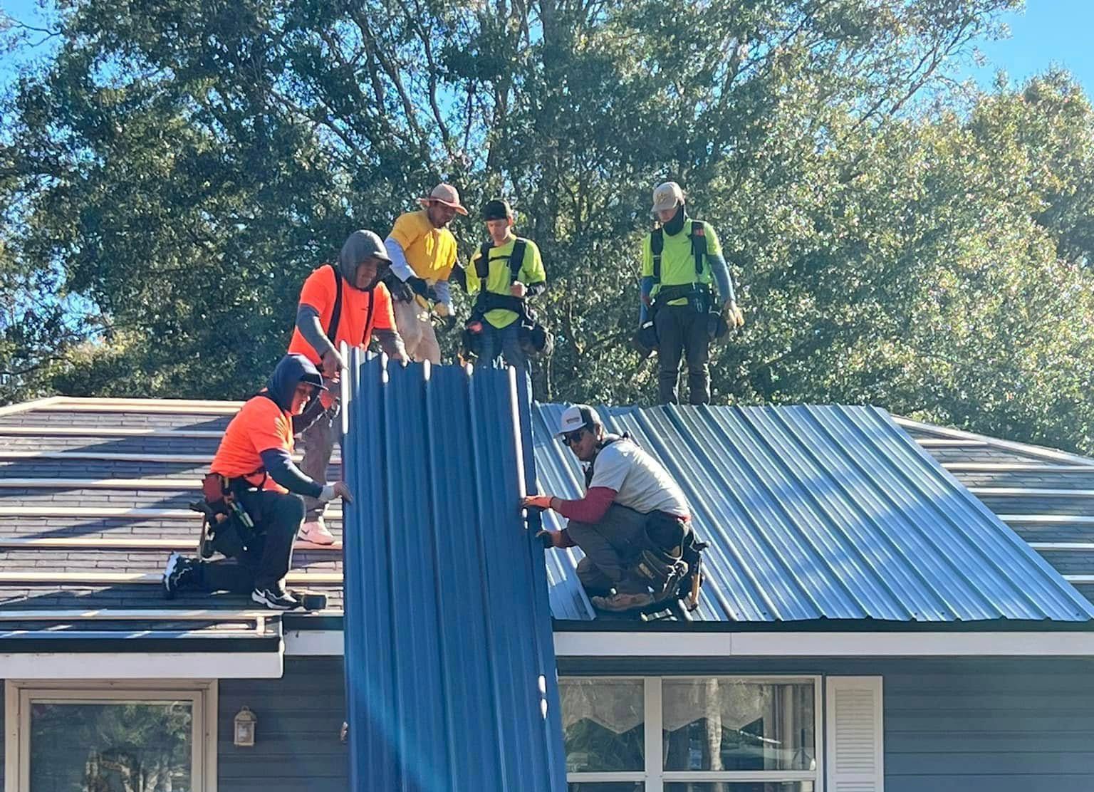 Professional metal roofers installing standing seam roofing panels safely.