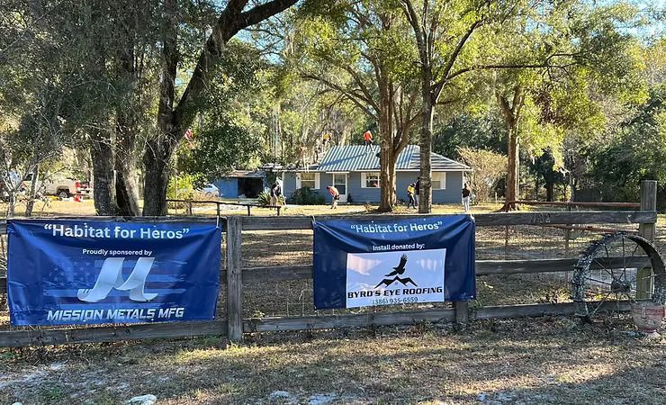 Two banners on a fence in front of a house that say