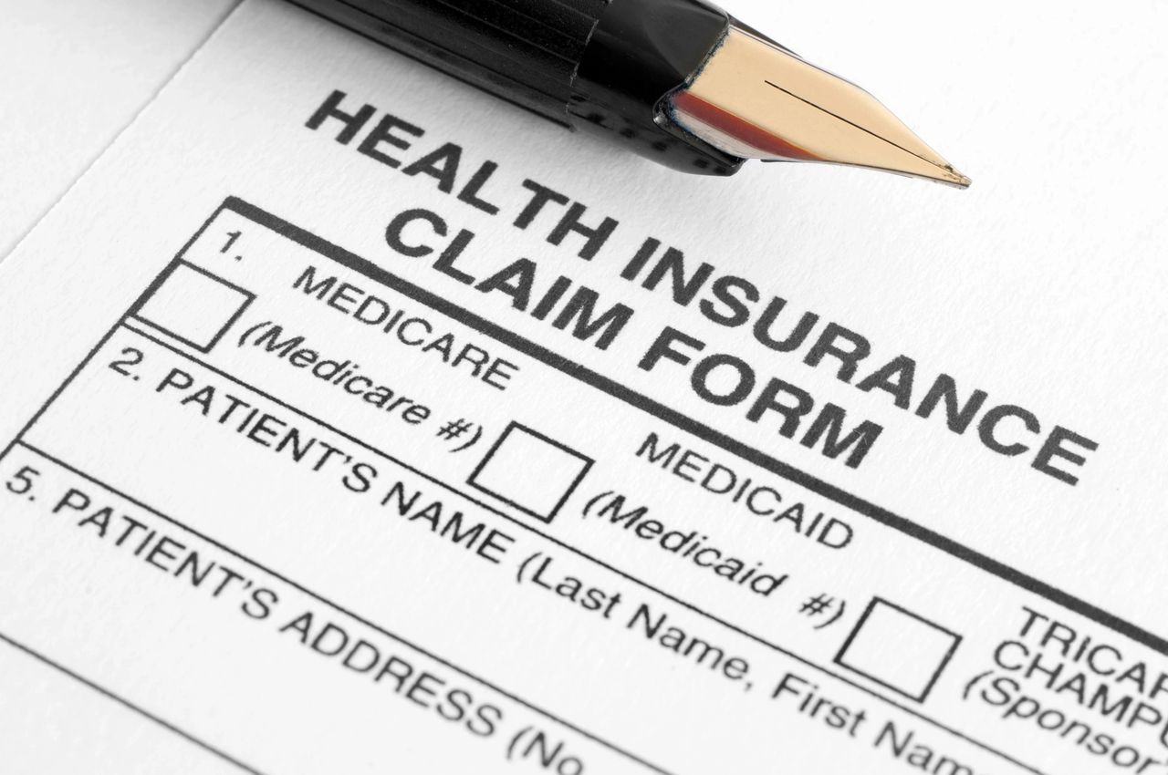 A pen sits on top of a health insurance claim form.