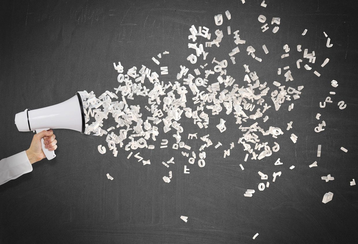 A hand is holding a megaphone with letters coming out of it.