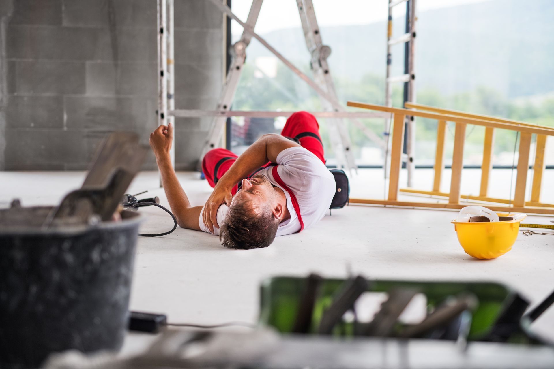 A man is laying on the floor after falling from a ladder.