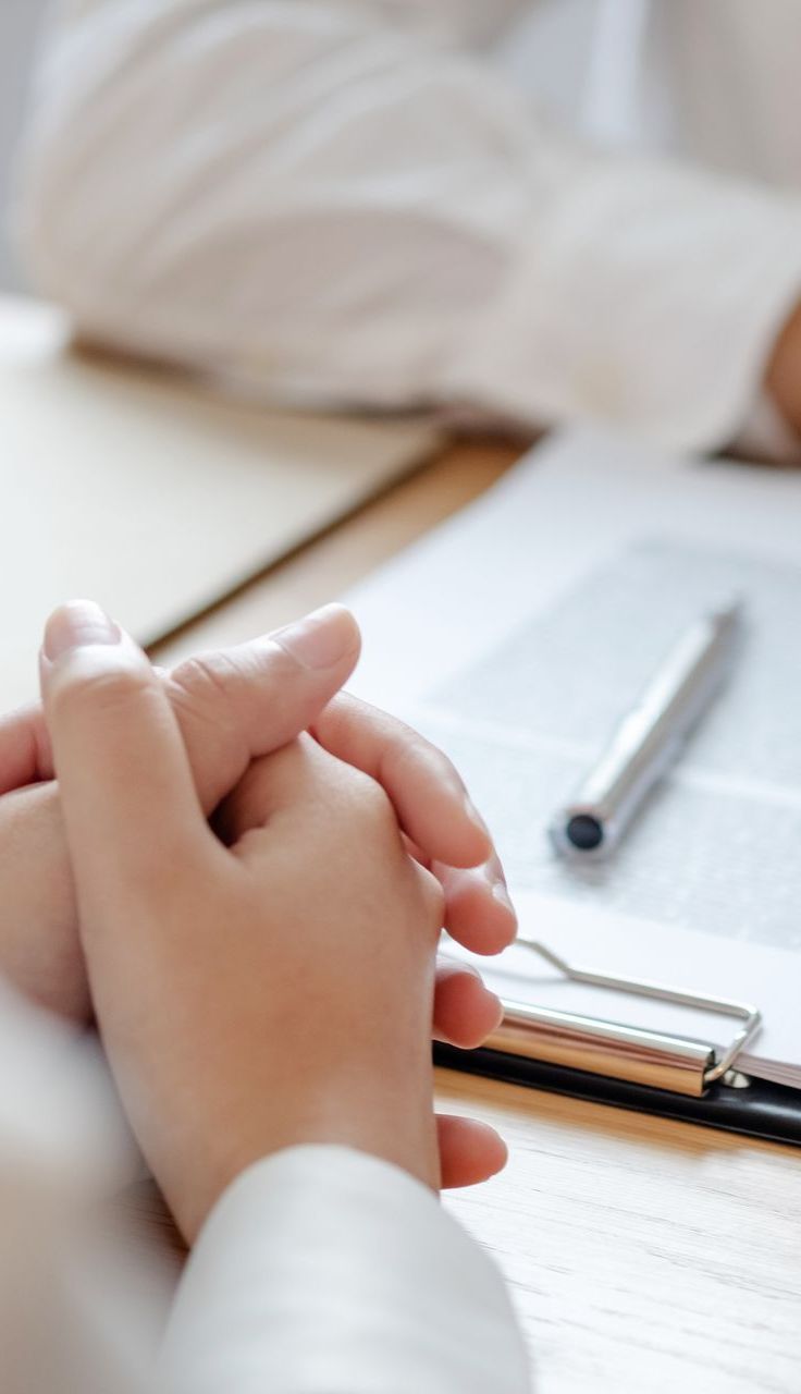 A person is sitting at a table with a clipboard and pen.
