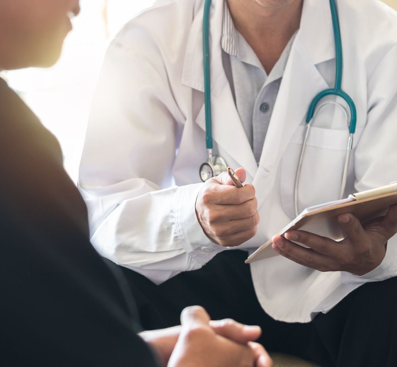 A doctor is talking to a patient while holding a tablet.