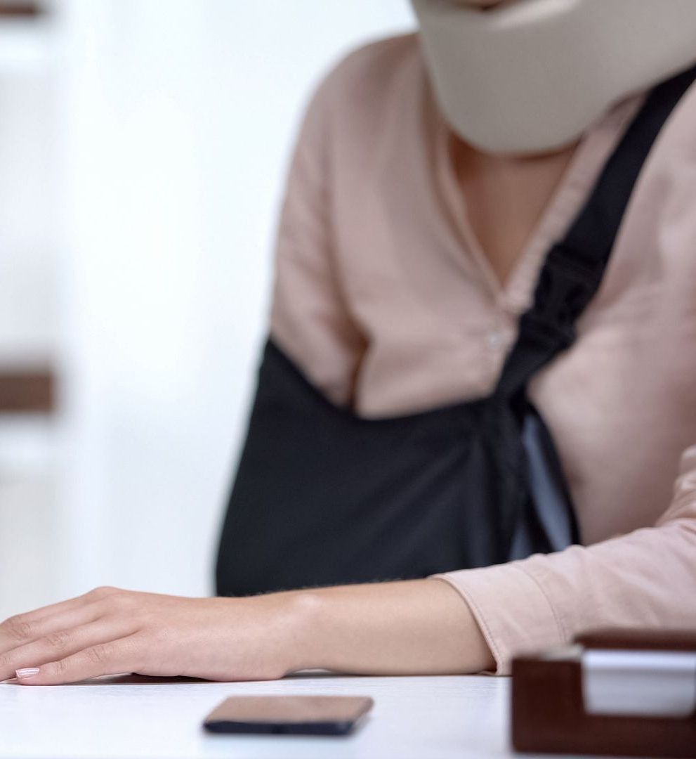 A woman wearing a neck brace is sitting at a desk.