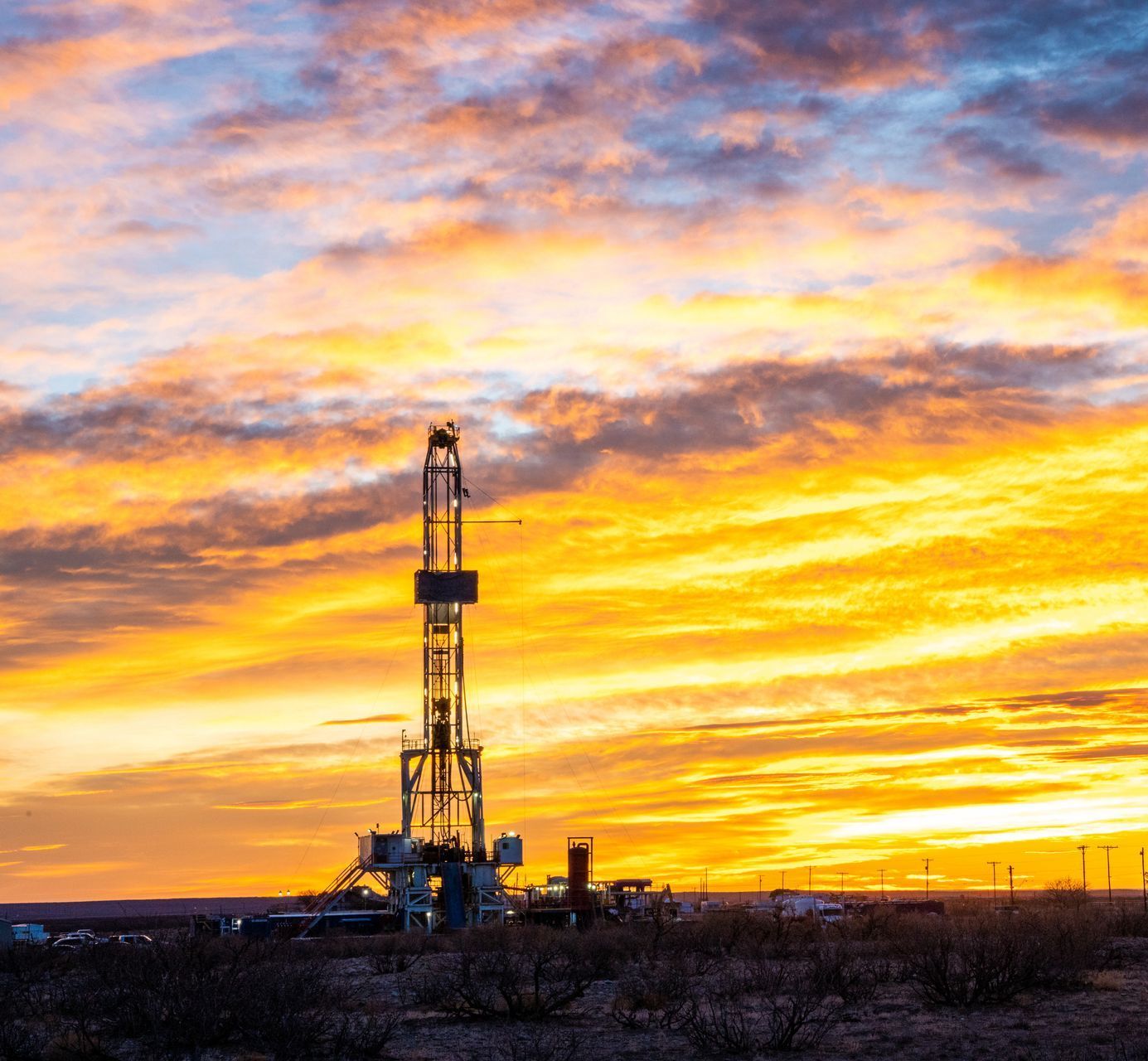 A large oil rig in the middle of a field at sunset.