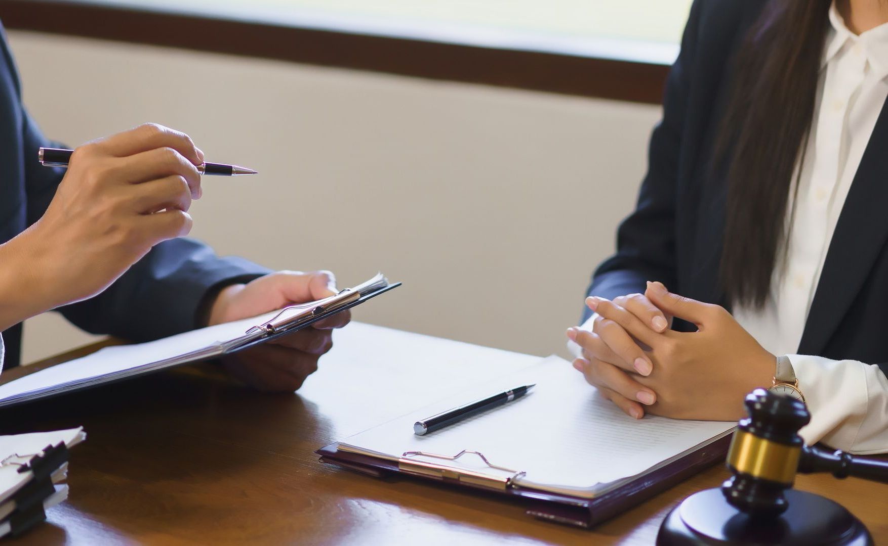 A man and a woman are sitting at a table with a clipboard and a gavel.