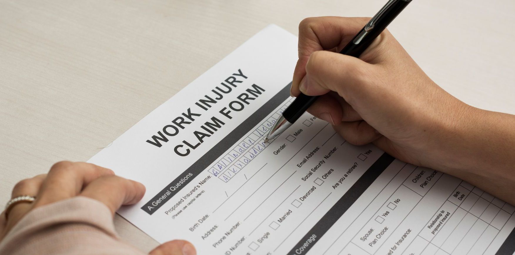 A person is filling out a work injury claim form.
