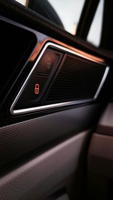 Car door lock buttons, red lock icon illuminated, silver trim, dark interior.