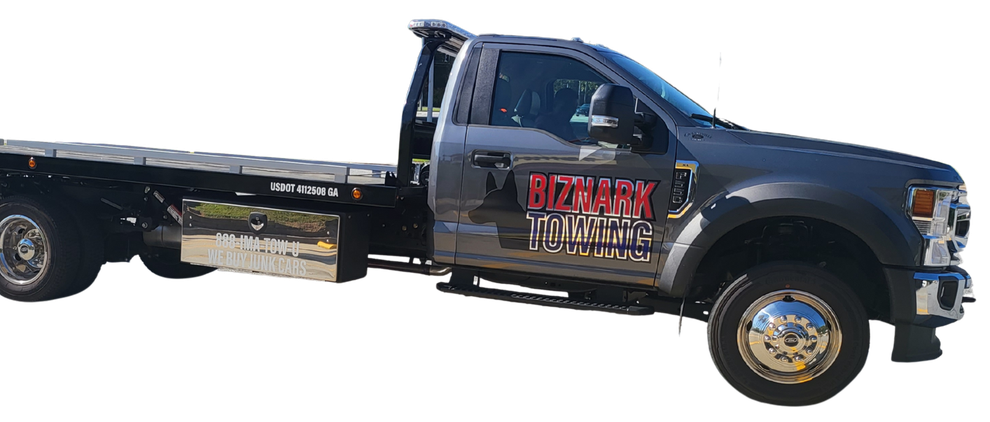 A gray flatbed tow truck with the name 