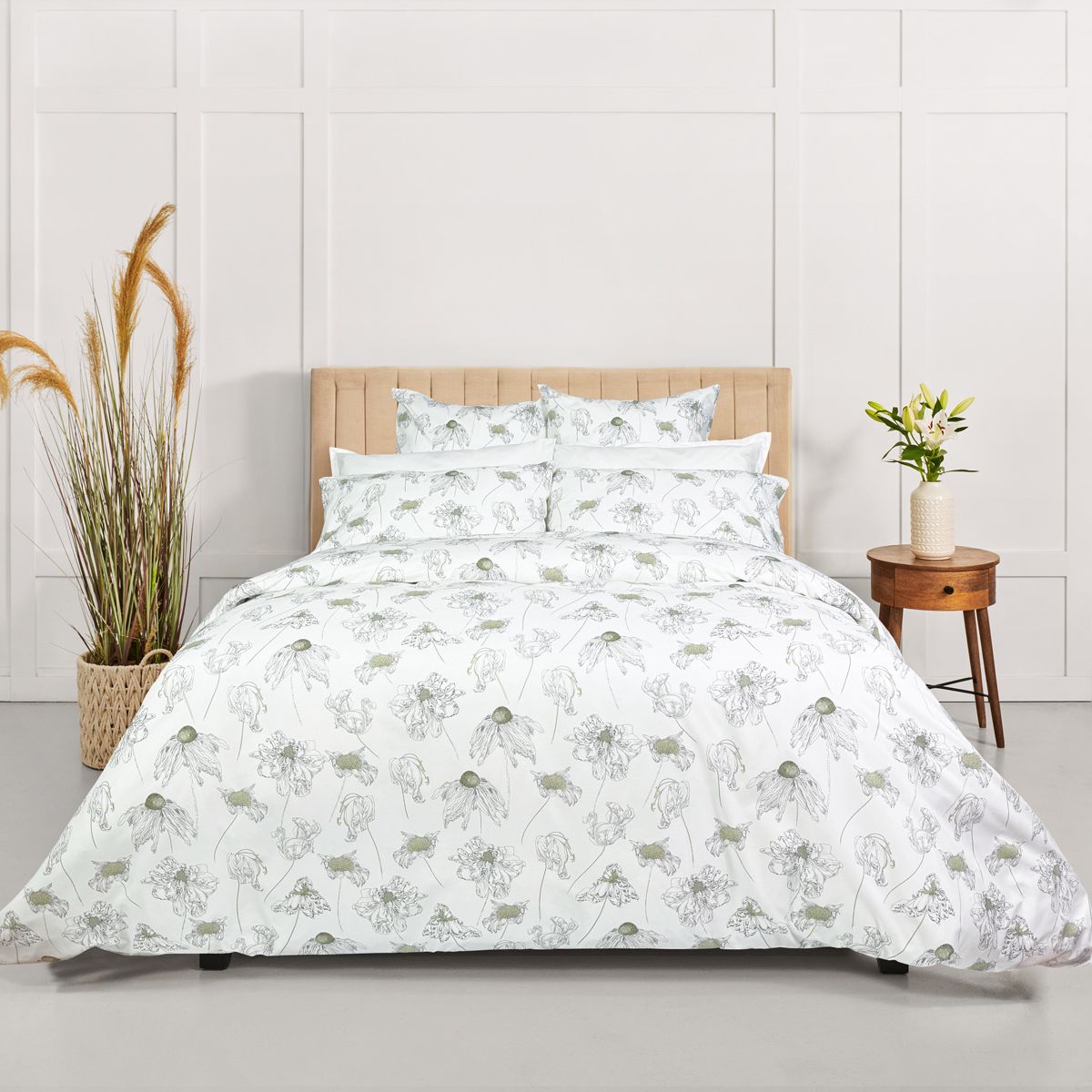 A bed made with white bedding featuring a green botanical print