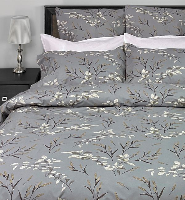 Gray duvet cover set featuring a botanical leaf print, styled on a bed with white pillows and a bedside lamp