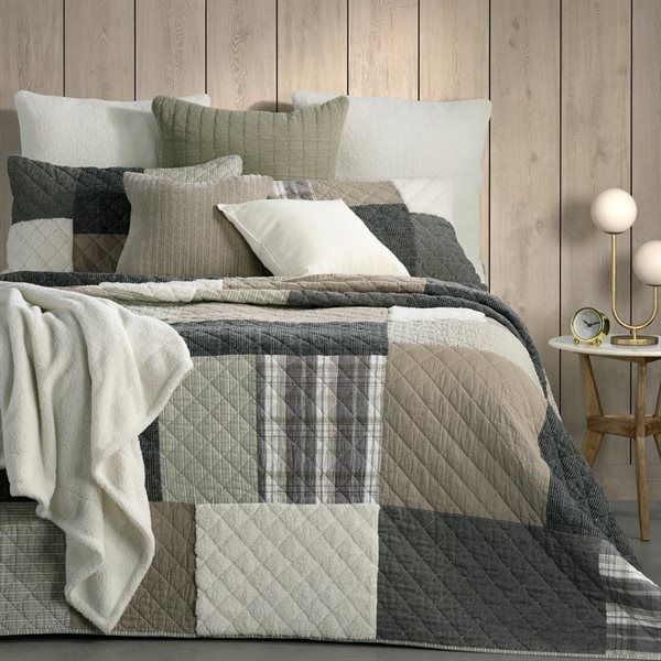 Bed with patchwork quilt and decorative pillows in neutral tones