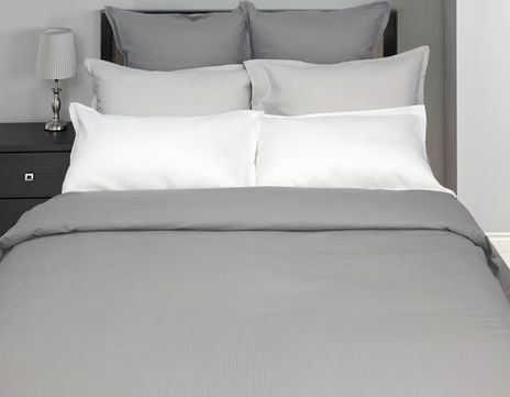 Gray bed with white and gray pillows and a matching gray comforter