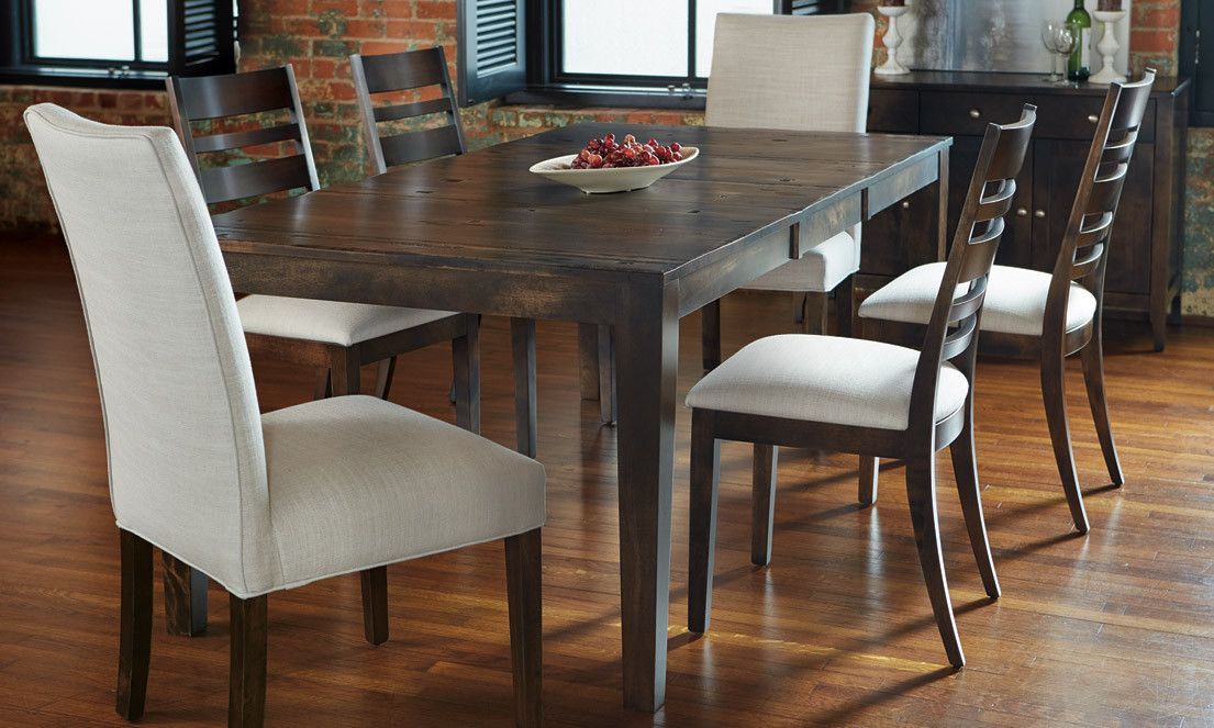 A dining table and chairs with a bowl of fruit on it.