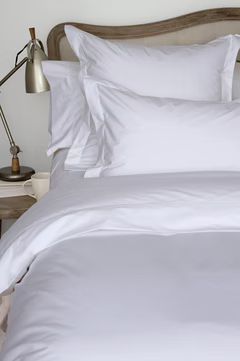 White bedding on a bed with a wooden headboard