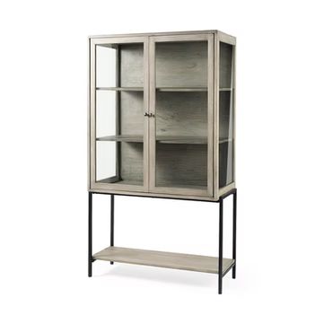 A tall, light-gray wooden display cabinet with glass doors on a black metal frame with an open bottom shelf