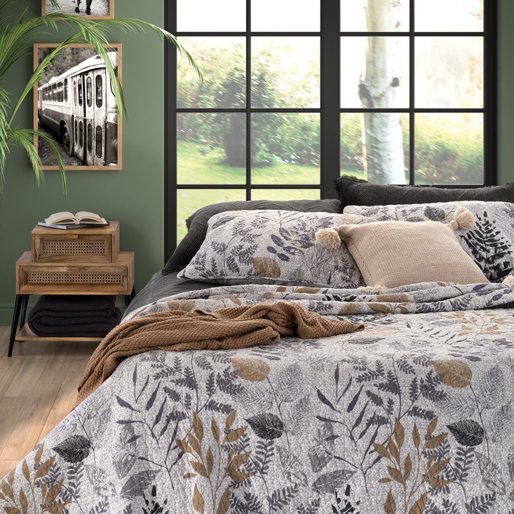 bed featuring a floral patterned quilt, pillows, and a knitted blanket