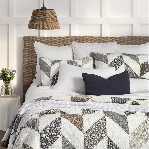 Bed with woven headboard, white bedding, patterned quilt