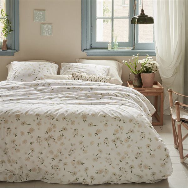 Bedroom with white floral bedding, blue window frames, and wooden side table