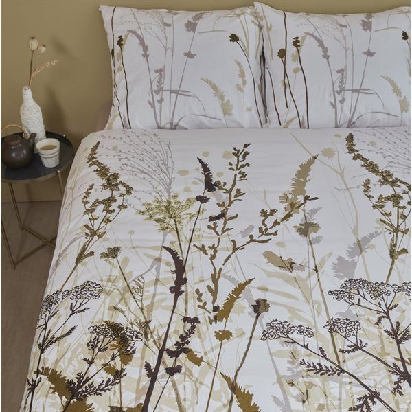 A bed with white bedding with a botanical print in shades of brown, olive and beige
