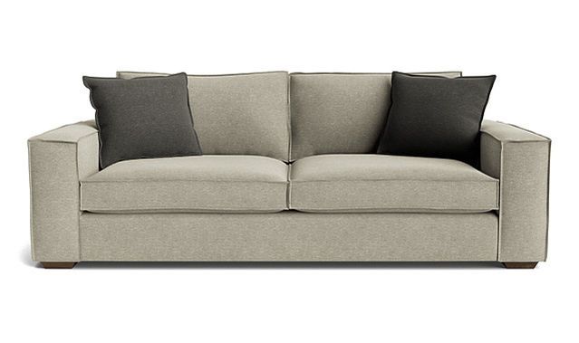 A beige couch with two black pillows