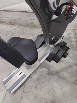 A close up of a recumbent exercise bike on a concrete floor.
