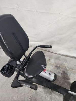 A black recumbent exercise bike is sitting on a concrete floor.
