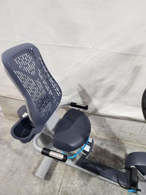 A recumbent bike is sitting on a concrete floor next to a white wall.