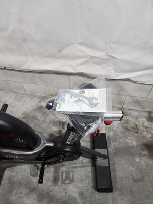 A spinning bike is sitting on a concrete floor next to a wall.