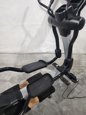 A black elliptical machine is sitting on a concrete floor.