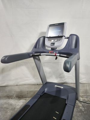 A treadmill is sitting on a concrete floor in front of a white wall.