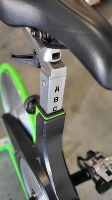 A close up of an exercise bike with a green wheel.