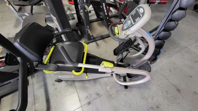 An elliptical machine is sitting on a concrete floor in a gym.