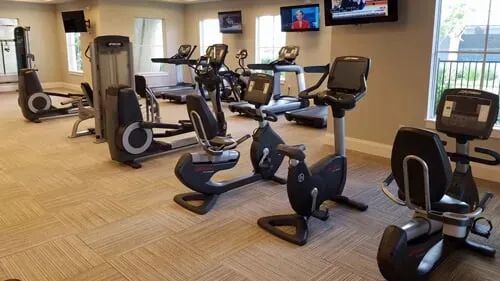 A gym filled with lots of exercise equipment and a television.