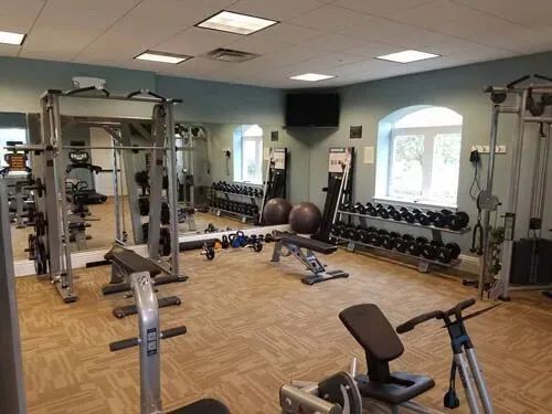 A large gym filled with lots of exercise equipment.