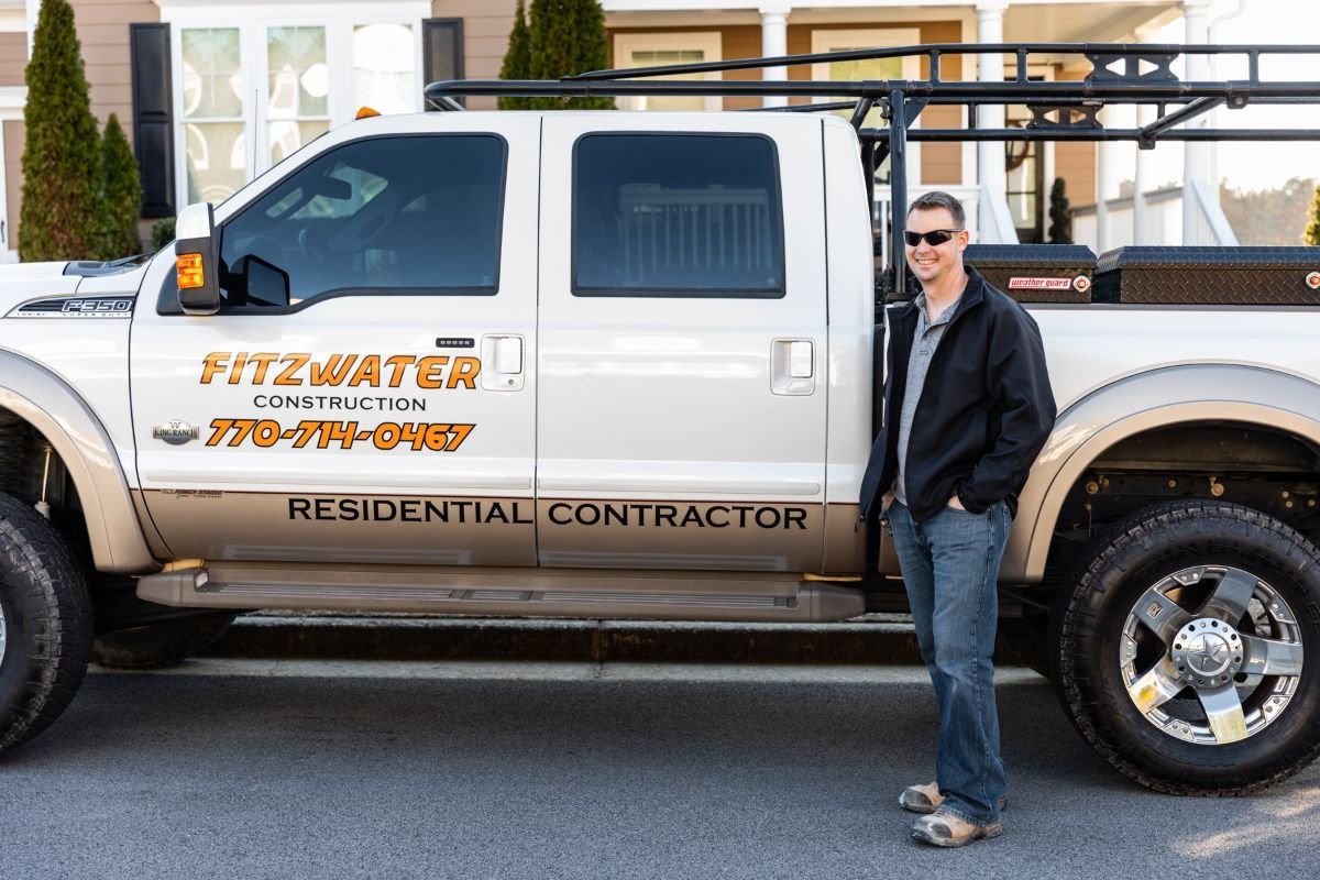 A man is standing next to a fitzwater residential contractor truck.